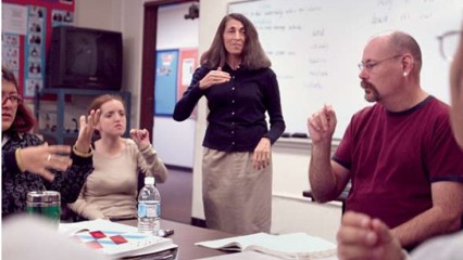 Accompanied by two of her deaf students, ESL Professor Sandie Linn learns ASL with interpreter David Janisch. 